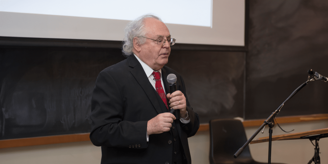 Rodger Loria his story about surviving the holocaust into a microphone in a lecture hall any Randolph-Macon College.