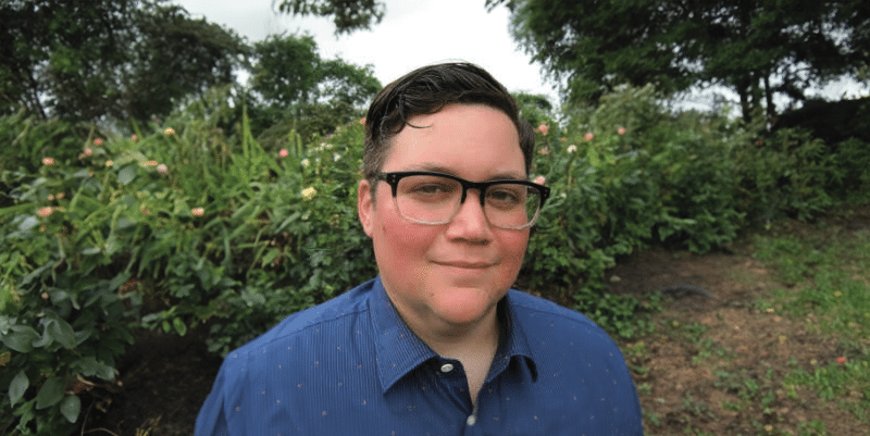 A man in glasses is standing in front of bushes at "Men in Place: An Evening with Miriam Abelson" event on Sept. 19.