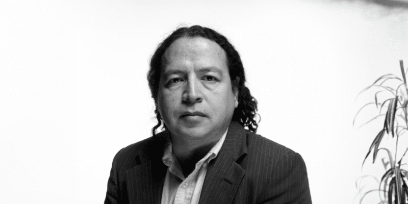 Lecture on entangled histories of U.S. and Indigenous people through a black and white photo of a man with long hair.