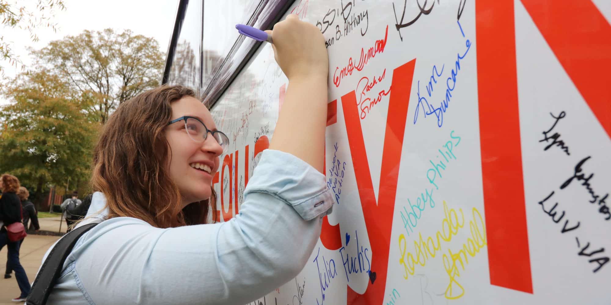 Student signs a banner