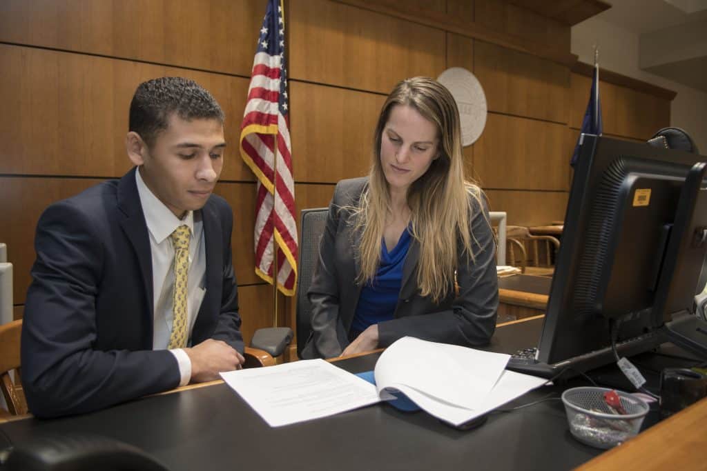 An RMC student sitting behind a desk in a court room