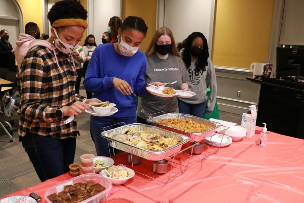 Students wait in line for food housed in buffet-style trays of food.