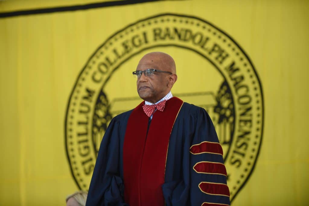 Dr Crutcher standing in front of a Randolph Macon Logo at commencement