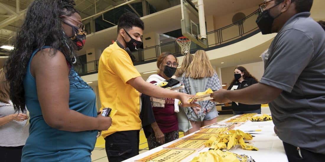 A student accepts a sticker and lanyard during move-in day.