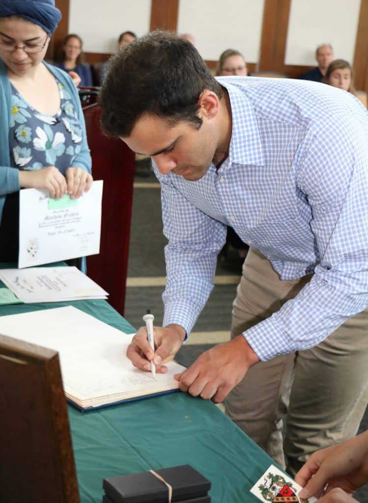 An RMC biology student signing a paper at the Tri beta Honor society Induction
