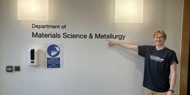 Will Adair point at a sign that reaeds "Department of Materials Science and Metallurgy" at cambridge university