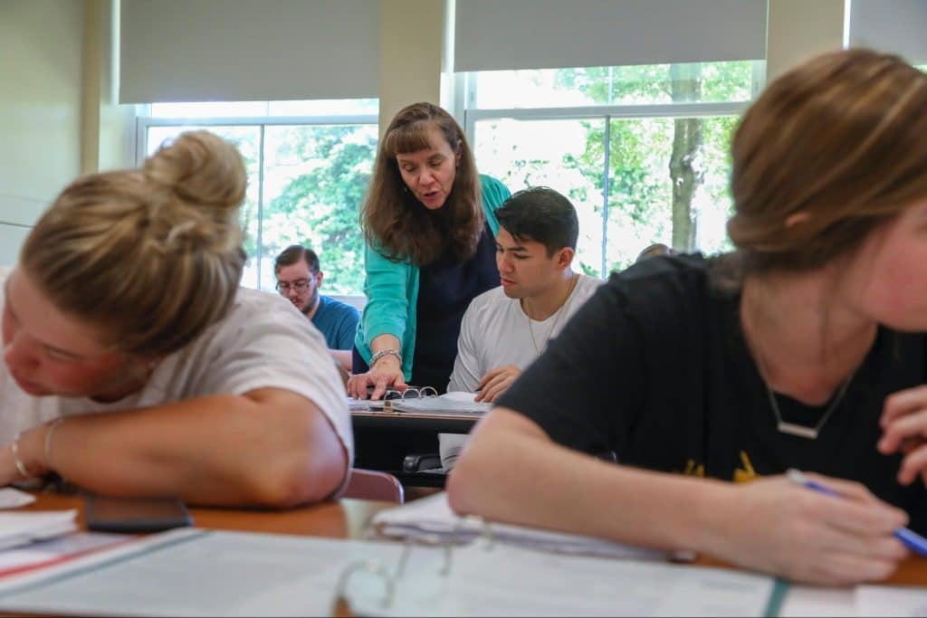 A teacher guiding students in an accounting classroom.