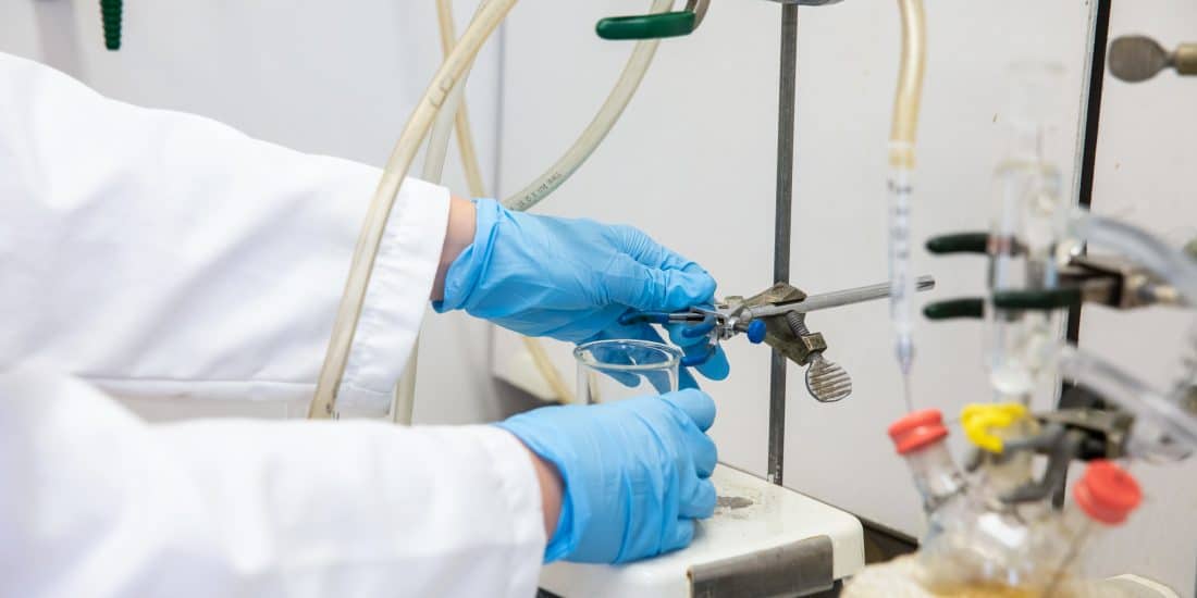gloved hands conduct an experiment in the RMC chemistry lab