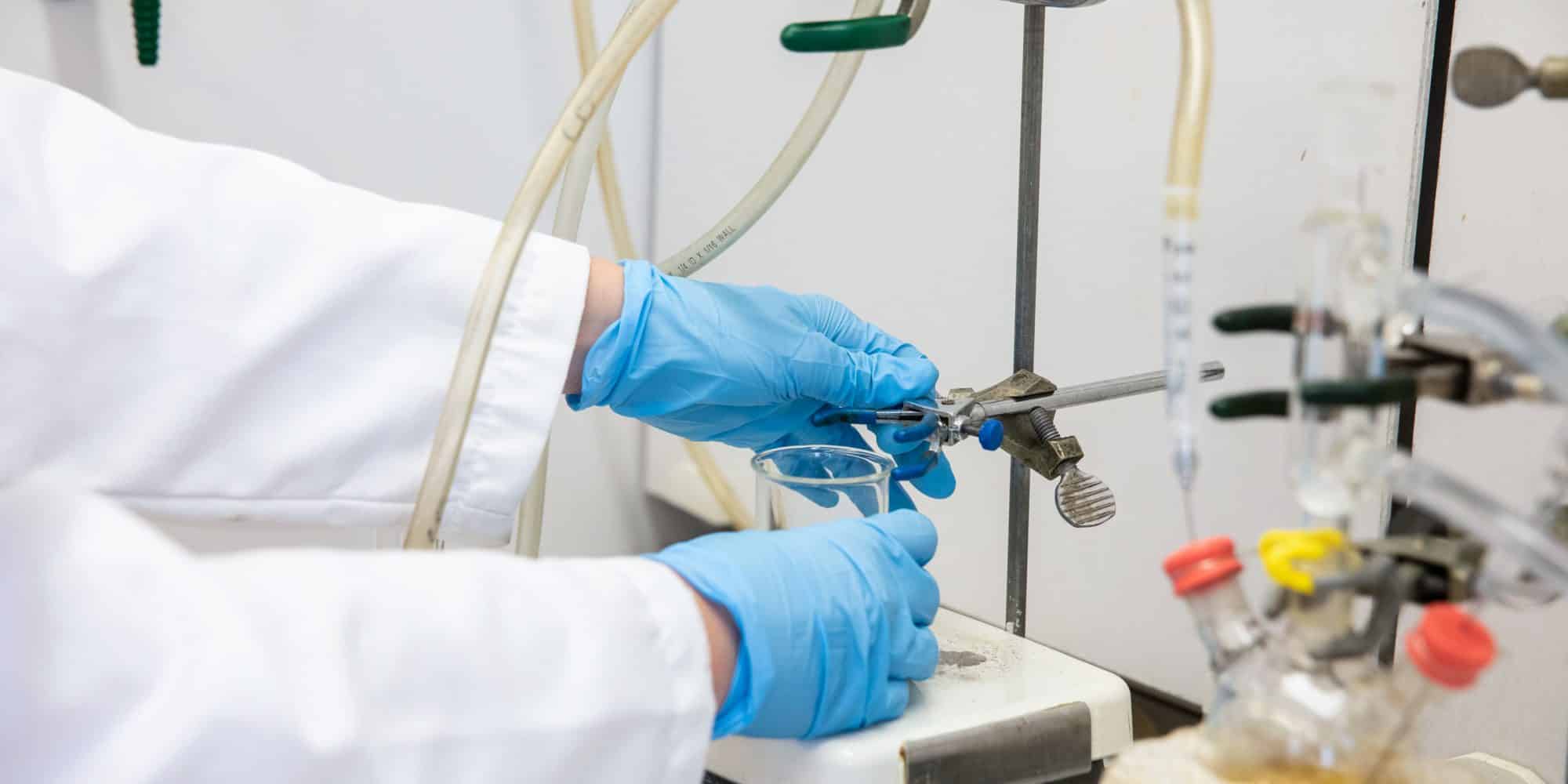 gloved hands conduct an experiment in the RMC chemistry lab