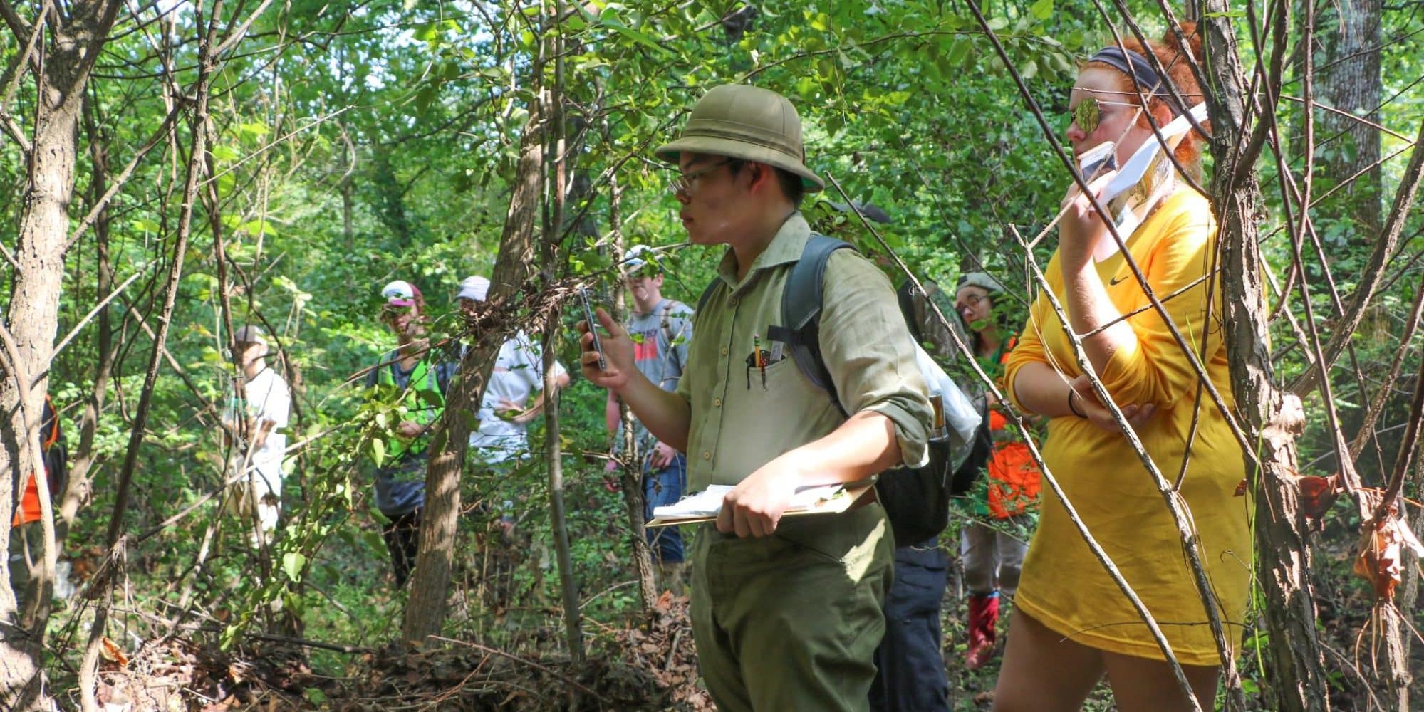 Randolph-Macon Environmental studies students standing among trees conducting field research