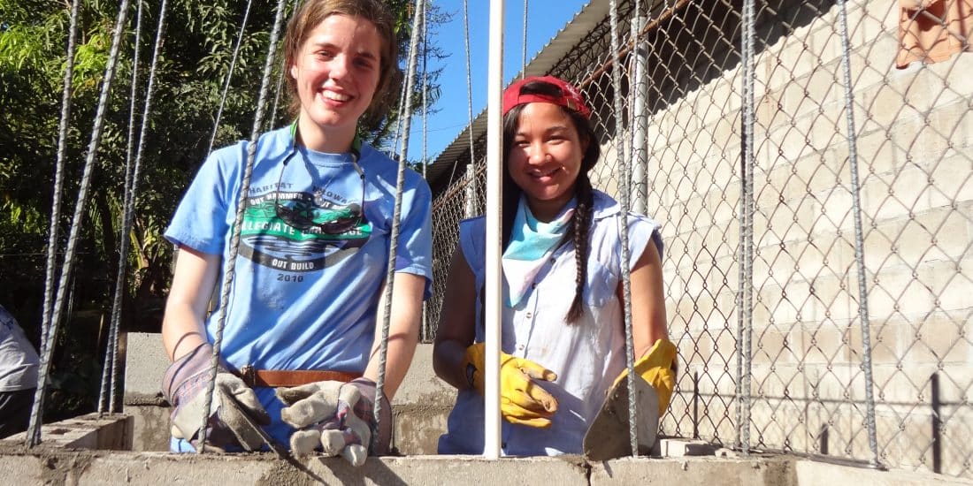Two female students build a foundation with cinder blocks in Costa Rica