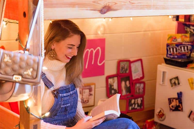 An RMC student reading a book in a dorm room