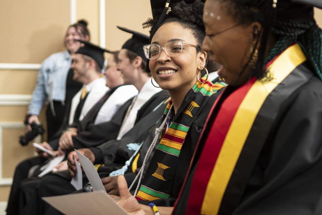 FEmale student in kente cloth and graduation regalia, looking forward