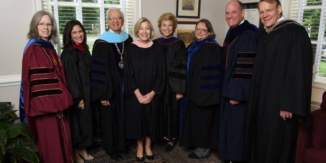 Eight adults in graduation robes