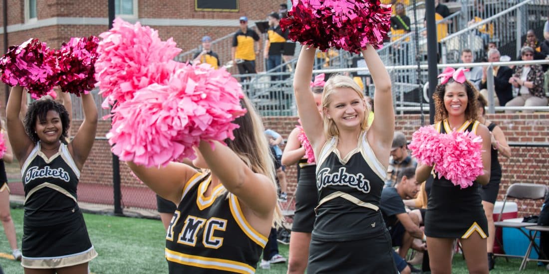 cheerleaders on football field with pom poms raised
