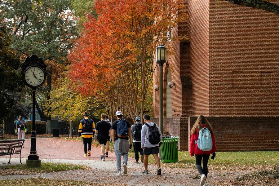 Students walking under fall foliate near old campus