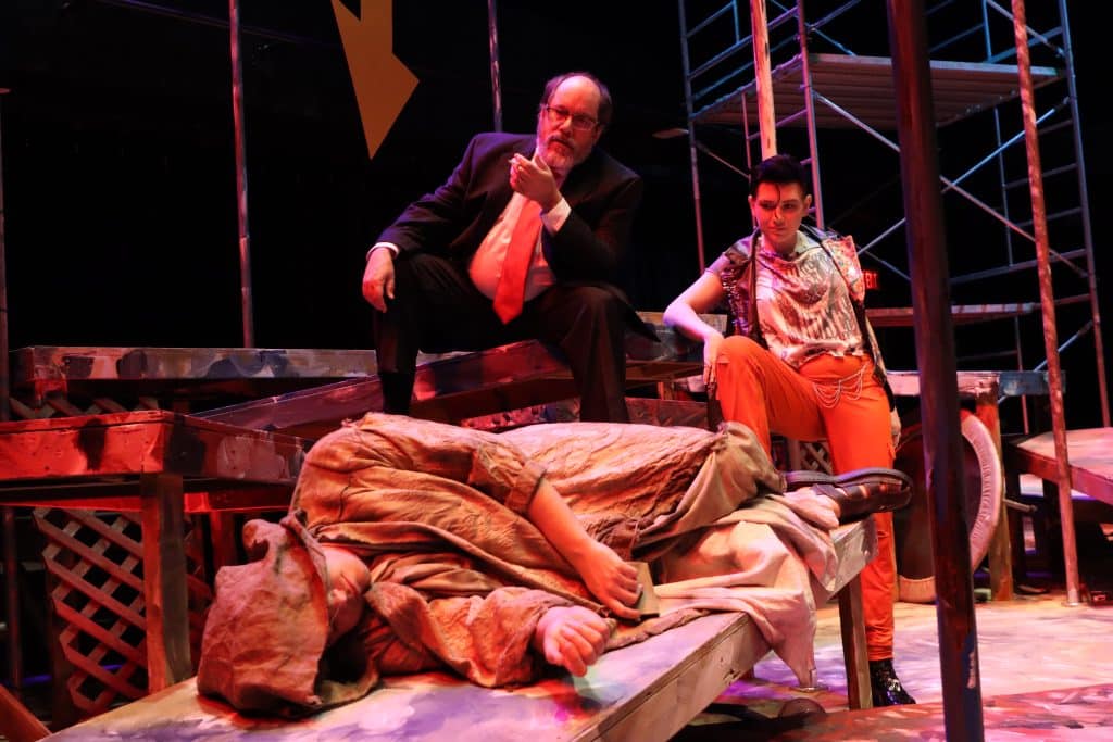 performers on stage with one man laying down