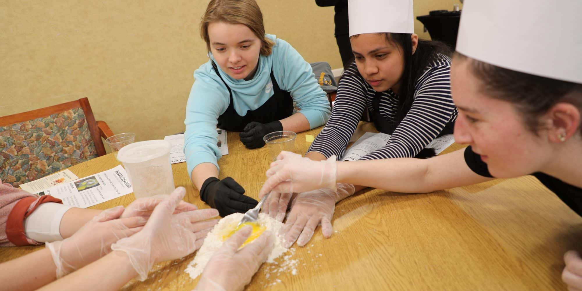 A group of people in the Honors Program preparing food at a table.