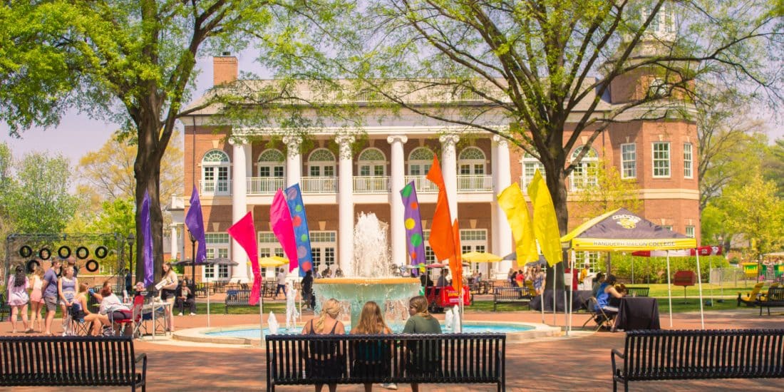 Admitted students sitting on benches in front of a fountain.