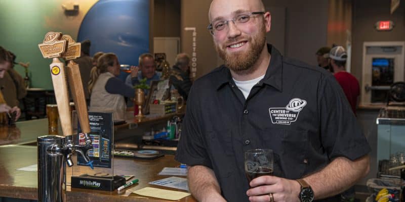 Nathan Landers smiling at COTU brewery with a beer in his hand.