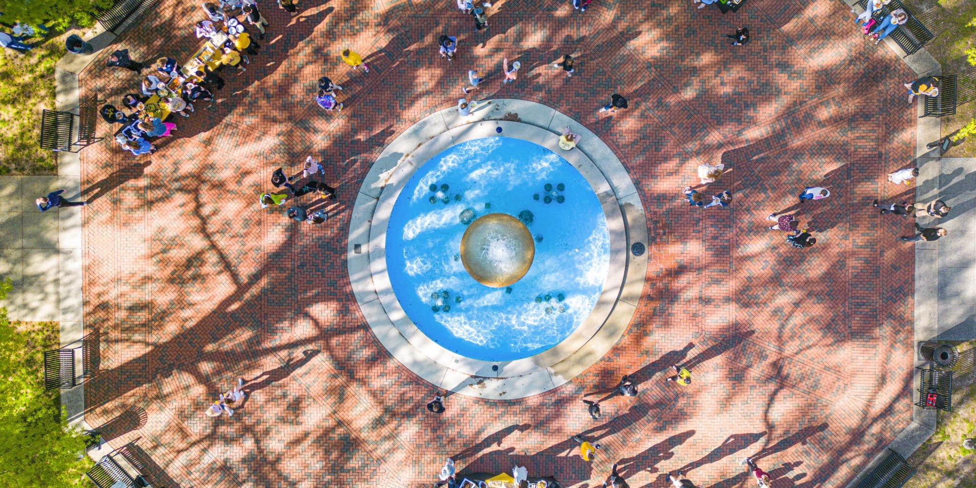 A group of current students standing around the RMC fountain, seen from above.