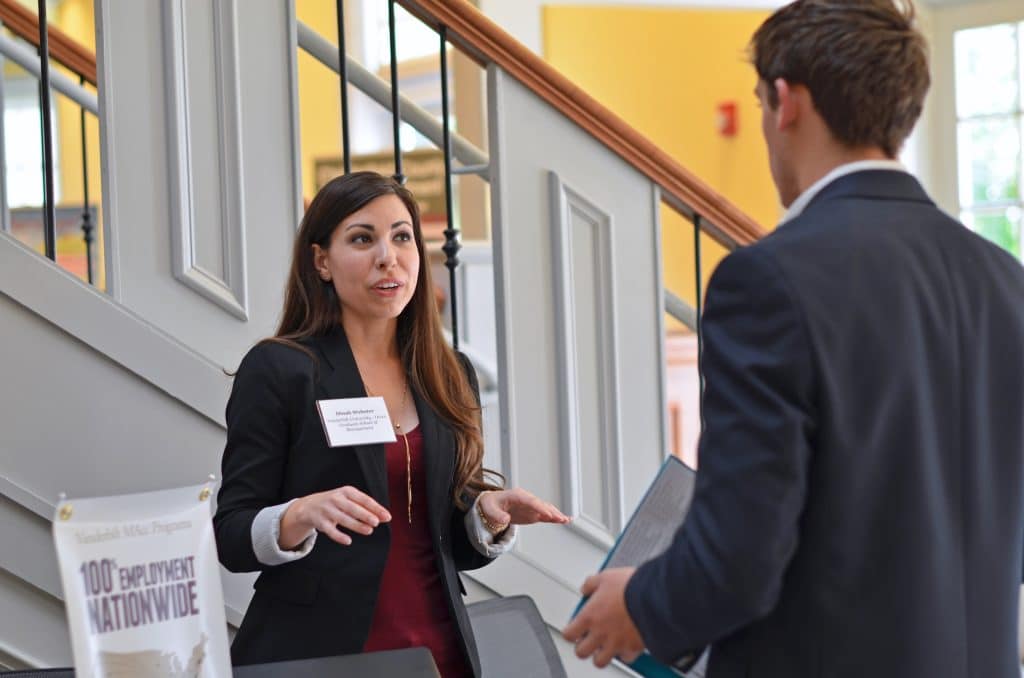 A man and woman discussing job fair resources.