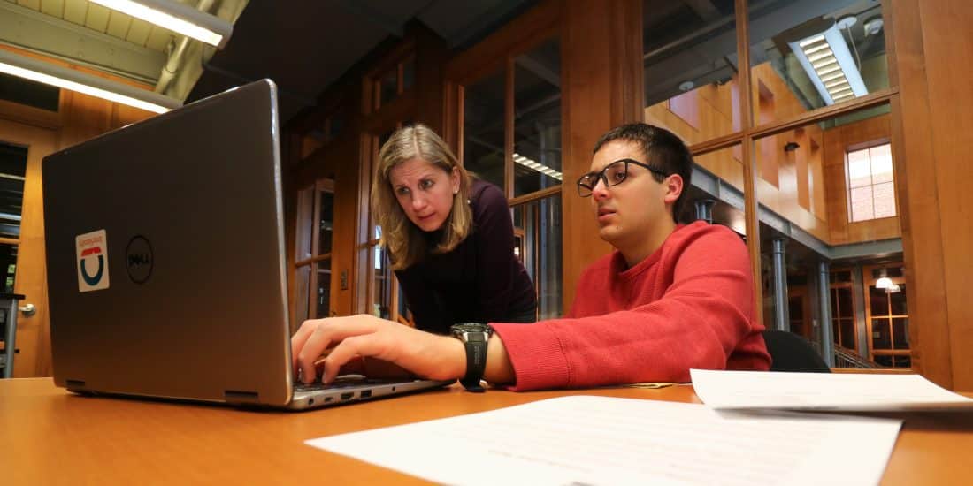 A RMC employee guides a student working on a laptop during a resume writing workshop in the Edge Career Center