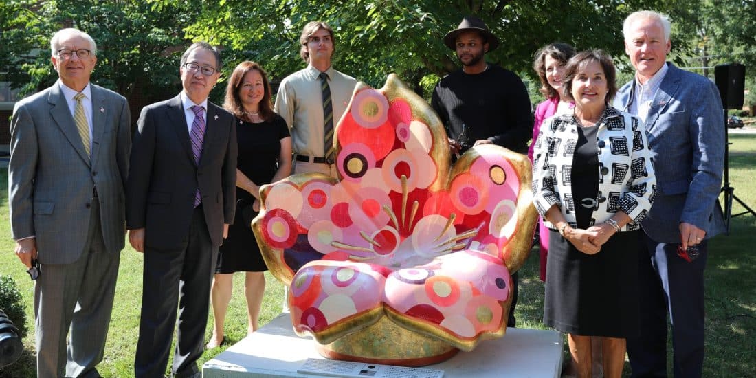 Tomita Koji, President Lindgren, Alex Goastier, and other RMC faculty standing around the Cherry Blossom Sculpture