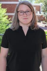 Robin M. Givens standing in front of a brick wall.