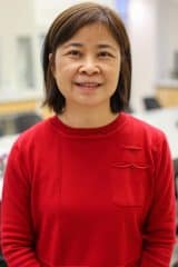 A woman in a red sweater standing in a lab named Suchen Lo.