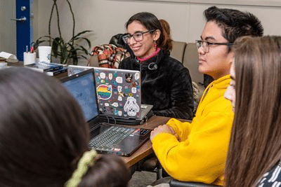 Helen Alvarez ’21, from student to published author, joins a group of people sitting around a table with laptops.
