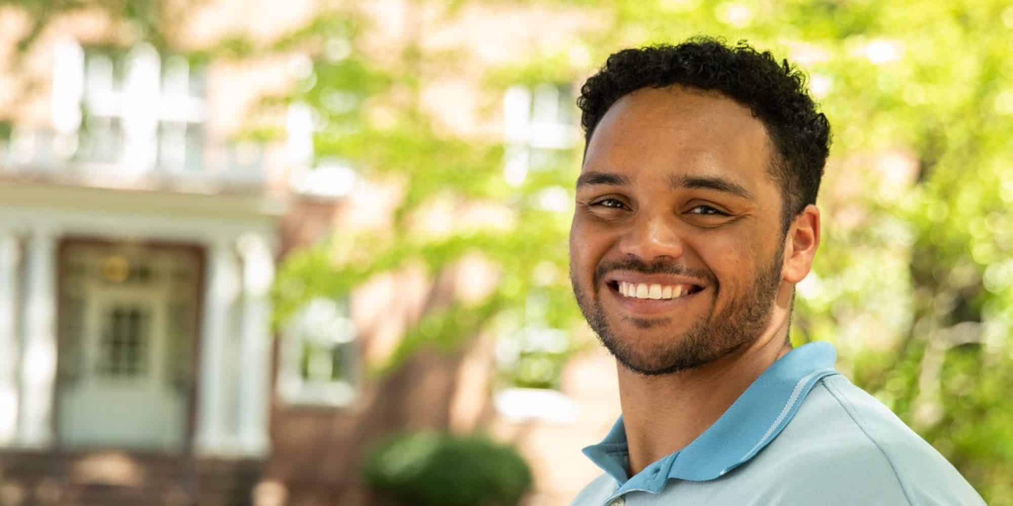 A young man in a blue shirt standing in front of a building.