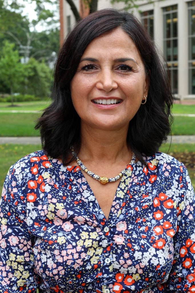 A woman in a floral shirt standing in front of a building that is mine.