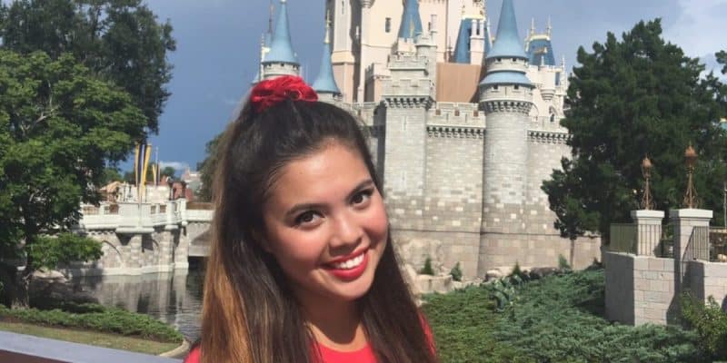 A young woman smiling in front of Cinderella Castle