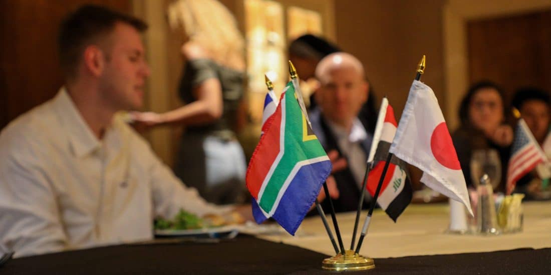 A group of people sitting at a table with flags.