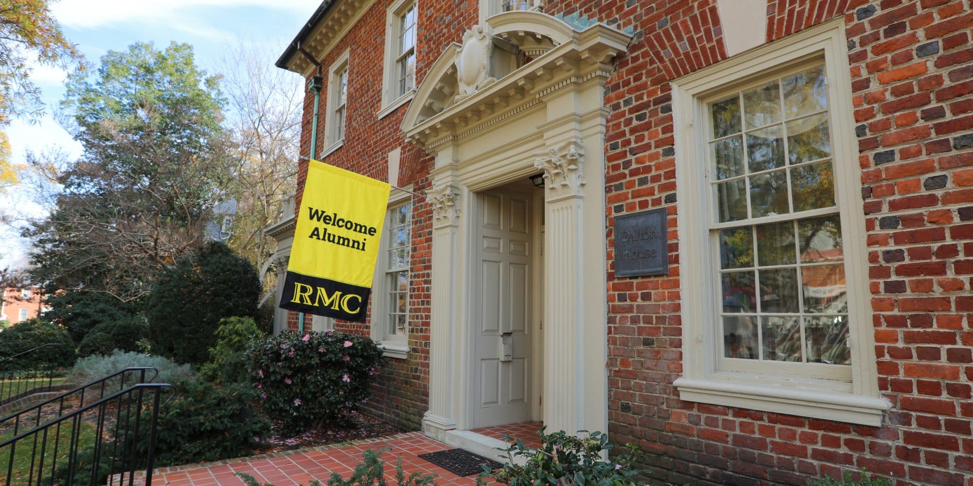 Dalton House, where the Office of Alumni Relations is located, with a yellow Alumni flag in front of it.
