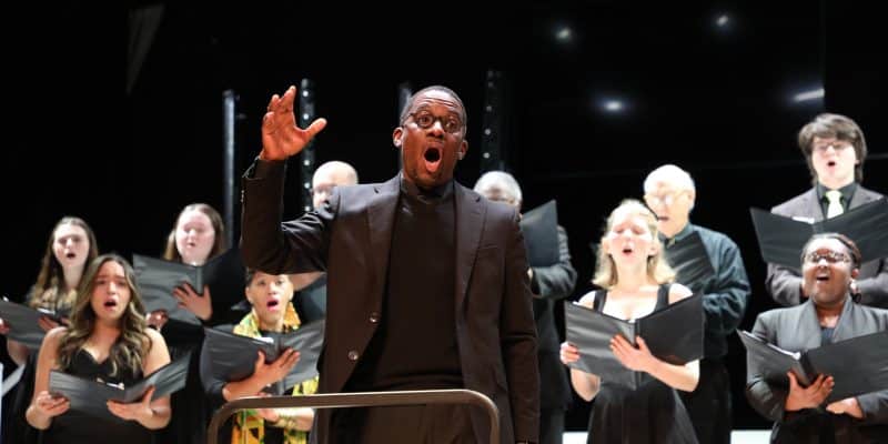 A man singing in front of a community during an MLK Day Commemoration, creating harmony.