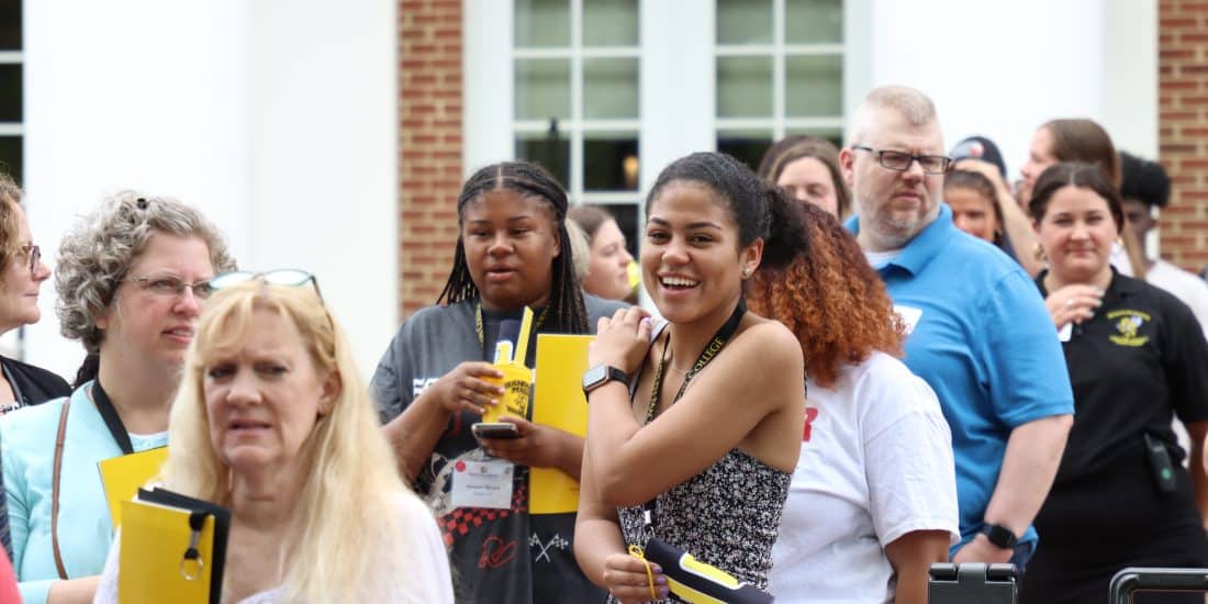 A group of students standing in a line outside of a building.