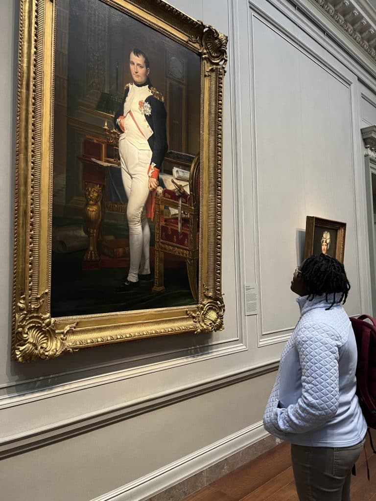 A woman looking at a painting of Napoleon.