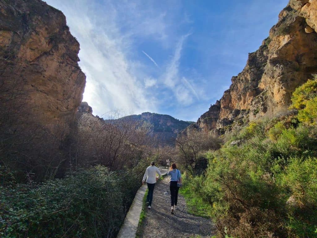 Two people walking down a path in a canyon.