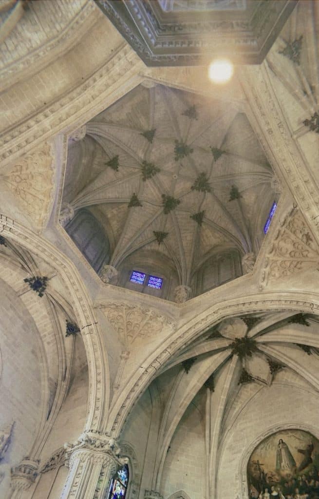 The ceiling of a church with a stained glass window.