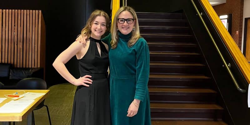 Two women posing for a photo in a performing arts center.