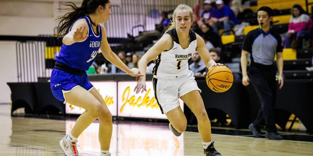 A female basketball player is dribbling down the court.