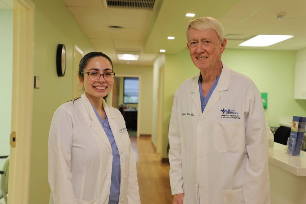A man and woman in white lab coats standing in a hallway.