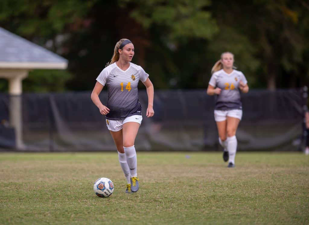 Female soccer player controlling the ball on the field during a match.