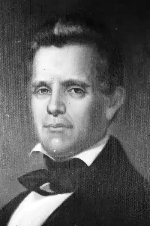 Black and white portrait of a college president in historical attire with a jacket and bow tie.