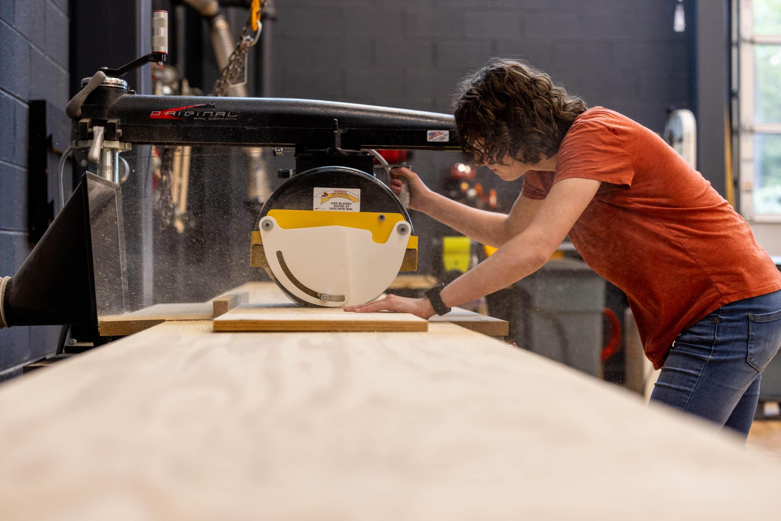 Student operating a saw in the scene shop.