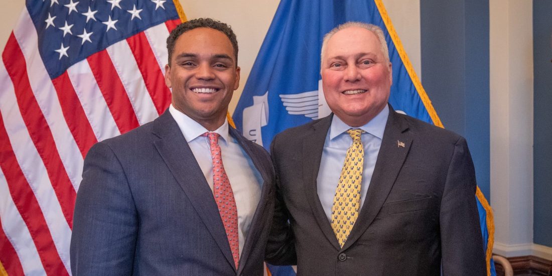 Ty Mills '22 and House majority leader Steve Scalise stand next to each other, smiling, with American and Louisiana state flags in the background.