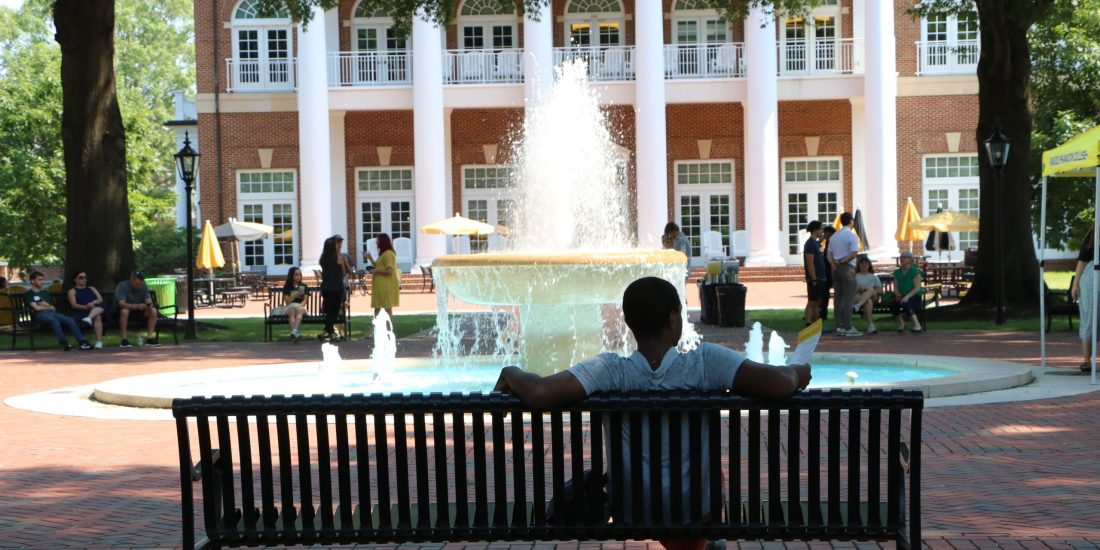 A RMC student sitting in front of a fountain.