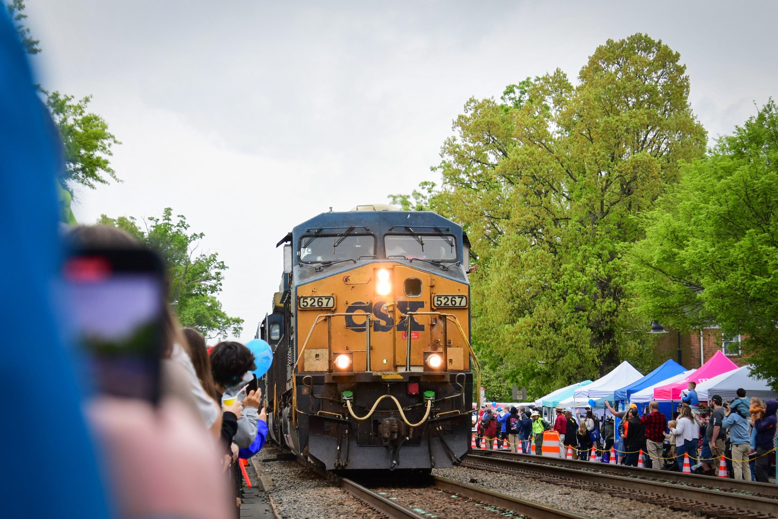 A CSX train approaches the station amidst eager onlookers.
